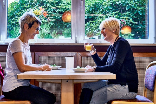 Zwei Frauen sitzen an einem Tisch und trinken Saft